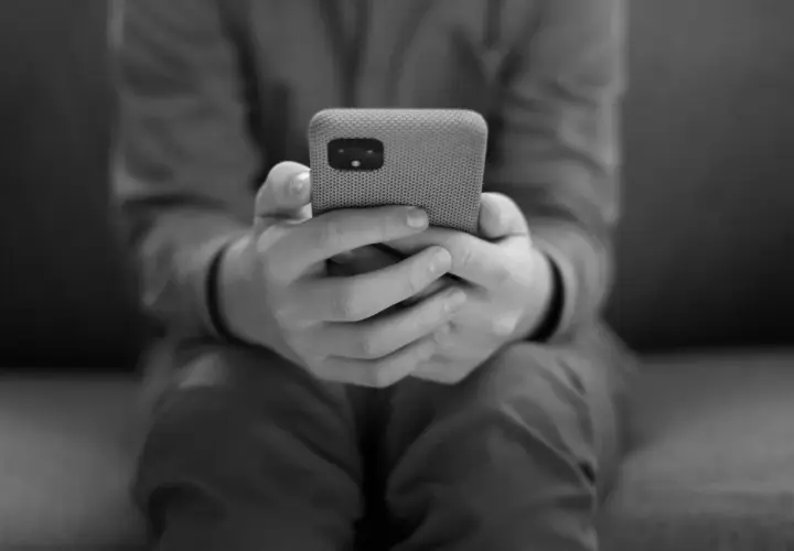 Dłonie trzymające telefon, symbolizujące uzależnienie od telefonu.