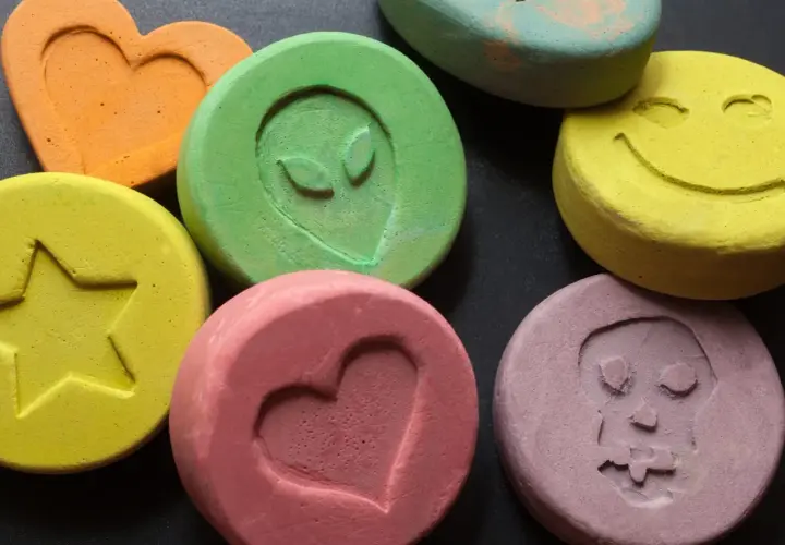 Kolorowe tabletki z symbolami: serce, gwiazda, uśmiech, kosmita, czaszka. Niektóre mogą zawierać mdma.