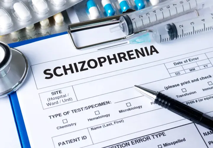 Lekarz wypełnia formularz "Schizofrenia", obok leżą strzykawki, stetoskop i opakowania leków, w tym risperidon.