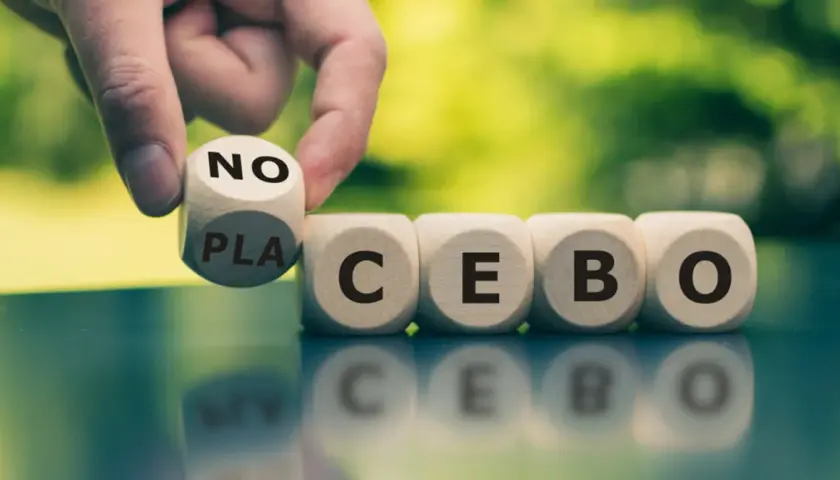 Palec odwraca kostkę z napisem "NO" na "PLACEBO", pokazując, czym jest efekt nocebo.